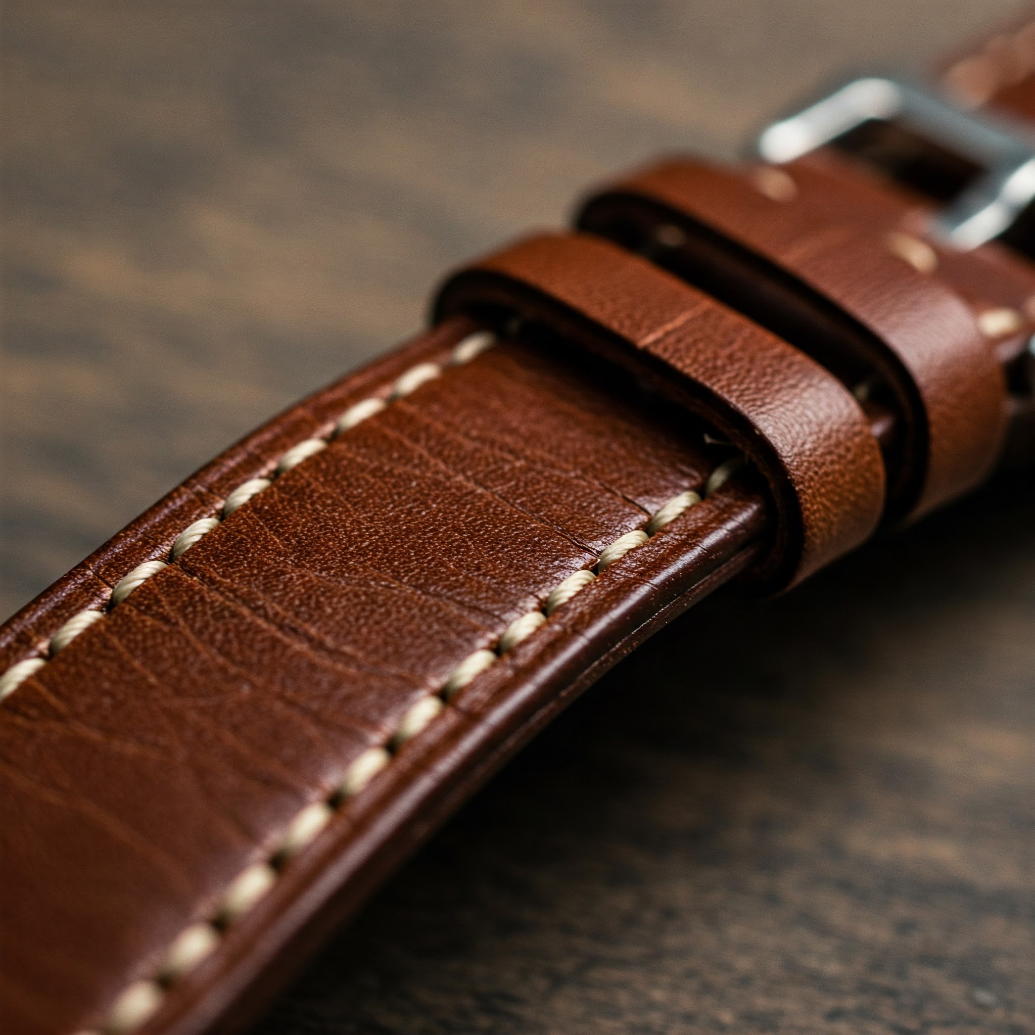 Close-up of a classic brown leather 16mm watch strap showing fine stitching and texture.