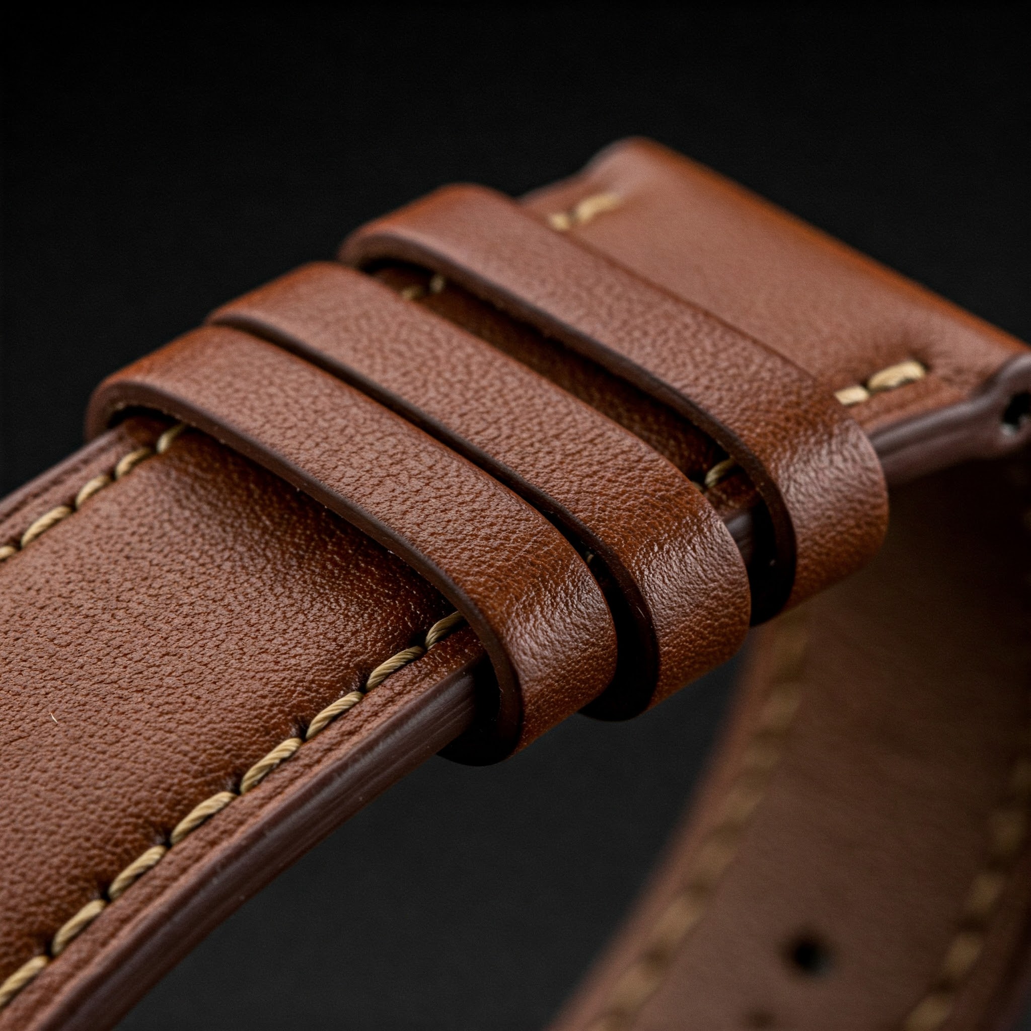 Close-up of a classic brown 20mm leather watch band showing the texture and stitching.