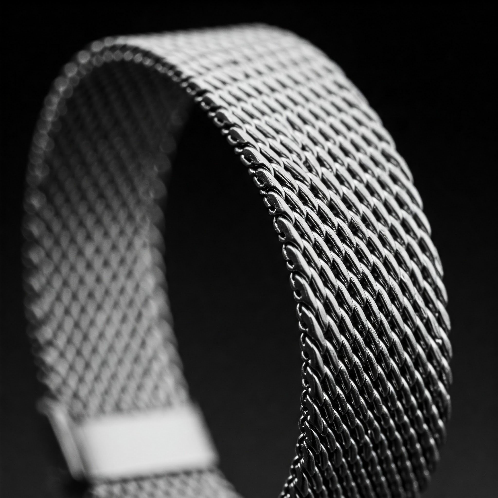 Close-up of a stylish silver milanese watch band showcasing its woven metal mesh texture.