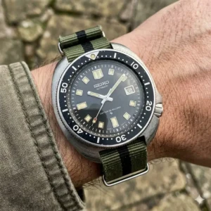 A vintage military-style watch on a green canvas strap, showing a casual approach to how to style vintage watches.